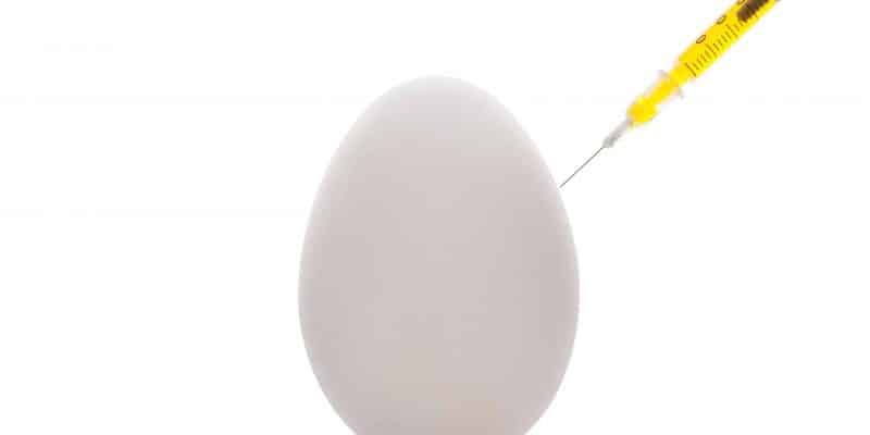 White egg yellow syringe injection on reflective surface.